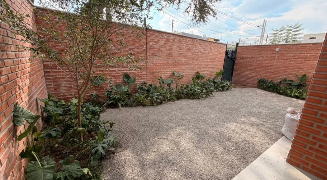 Jardín privado de planta baja con muro de ladrillo
