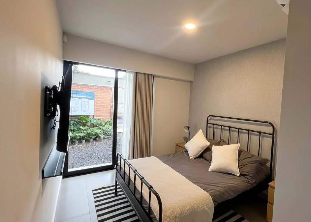 Recámara del departamento muestra con ventanal de piso a techo al jardín