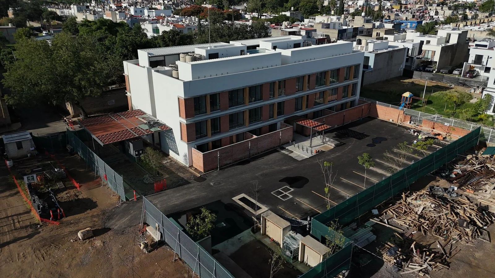 Torre 1 terminada, con el estacionamiento pavimentado y la pérgola de barro en el acceso