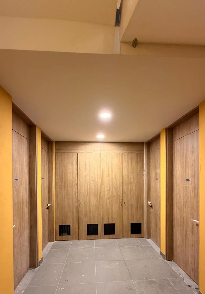 Vestíbulo interior de la Torre 1 con las puertas de madera, el piso colocado y la iluminación encendida